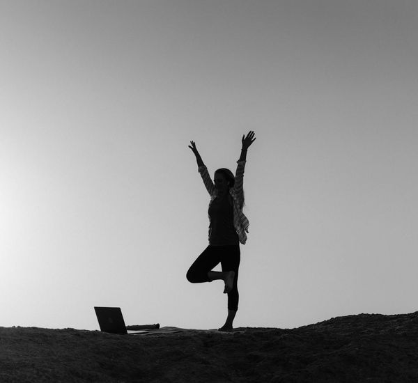 Silhouette of a person in a yoga pose against a bright, serene sunrise.
